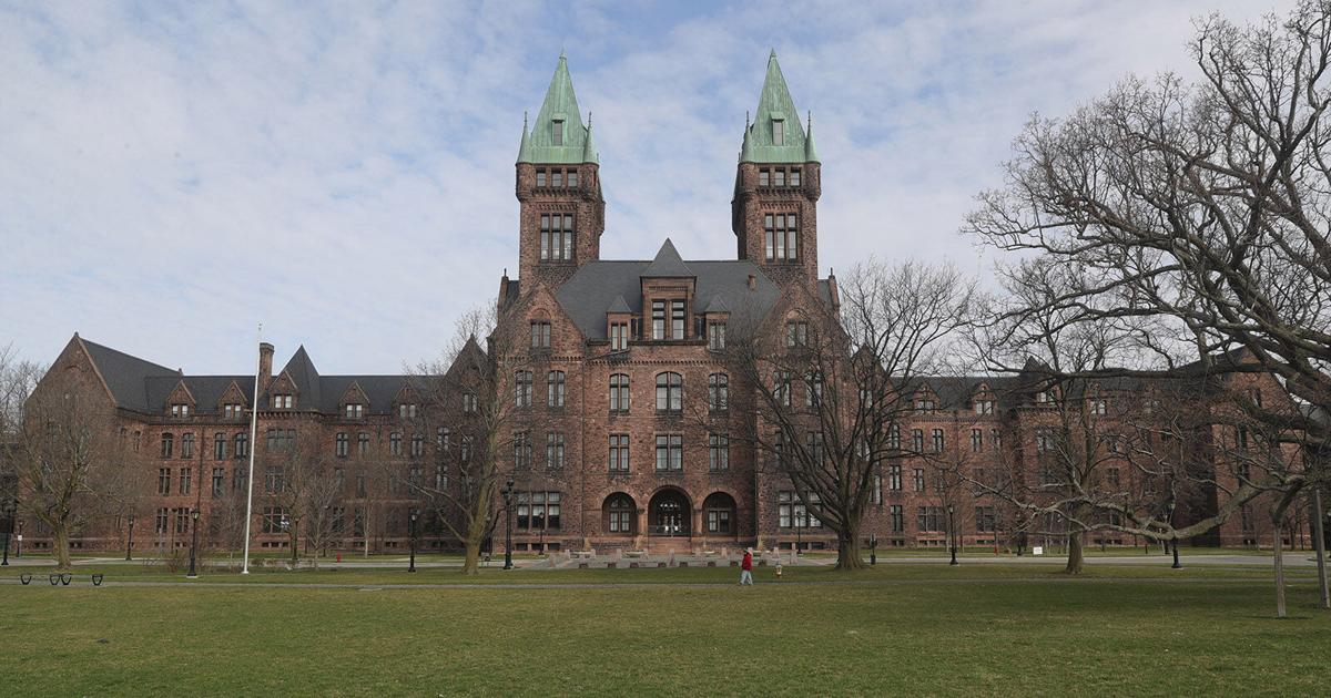 Historic brick university building with twin towers, lawn