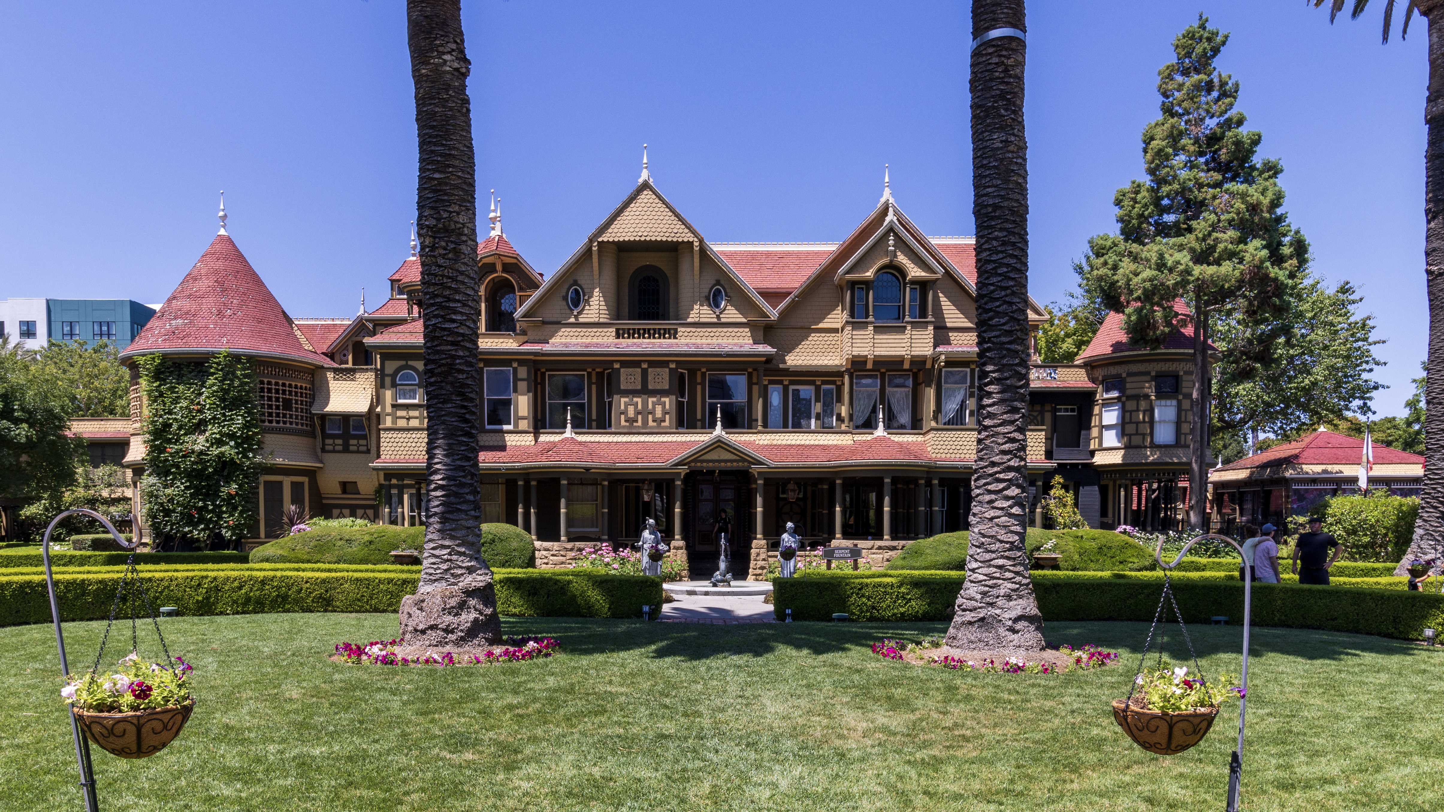 Victorian mansion with red turrets and palm-lined garden