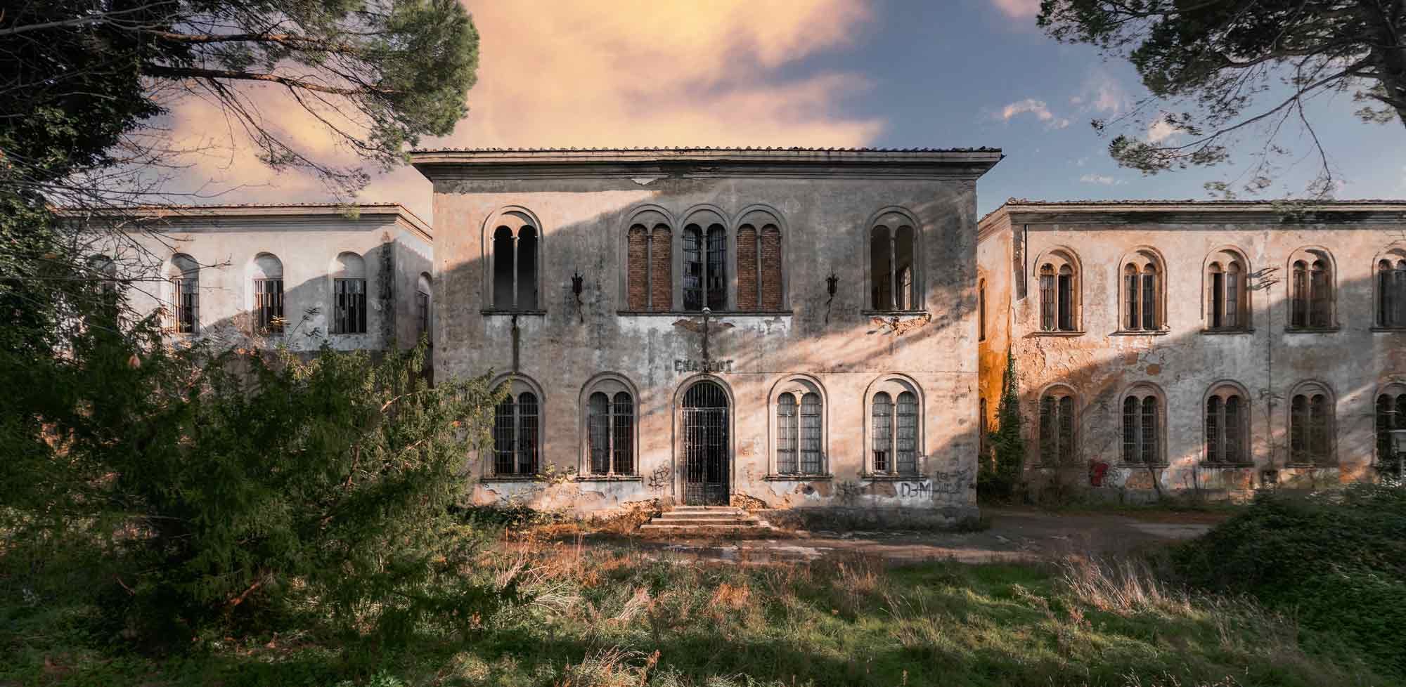 Abandoned stucco villa with arched windows at sunset