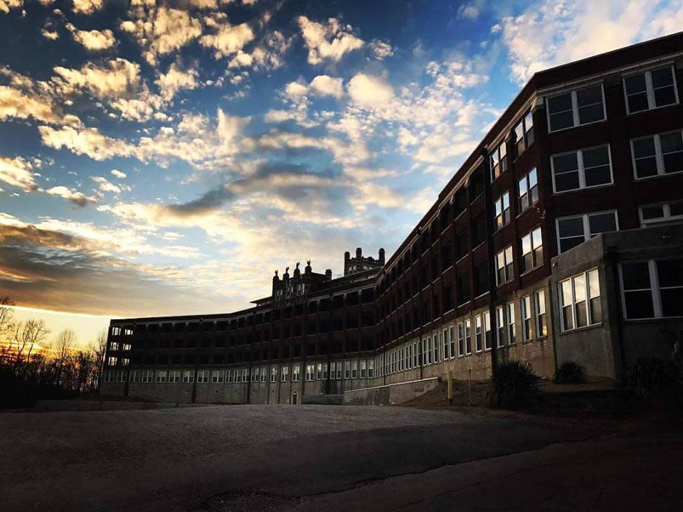 Abandoned brick hospital building at dusk under clouds