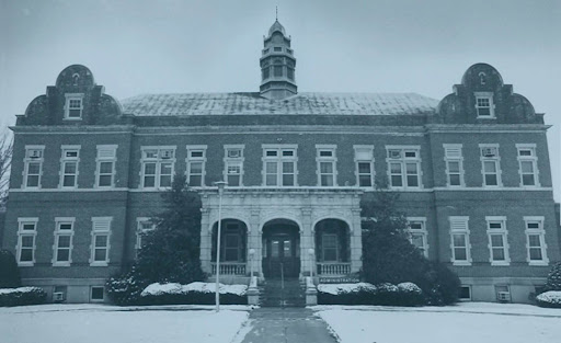 Snow-covered brick building with arched entrance and cupola