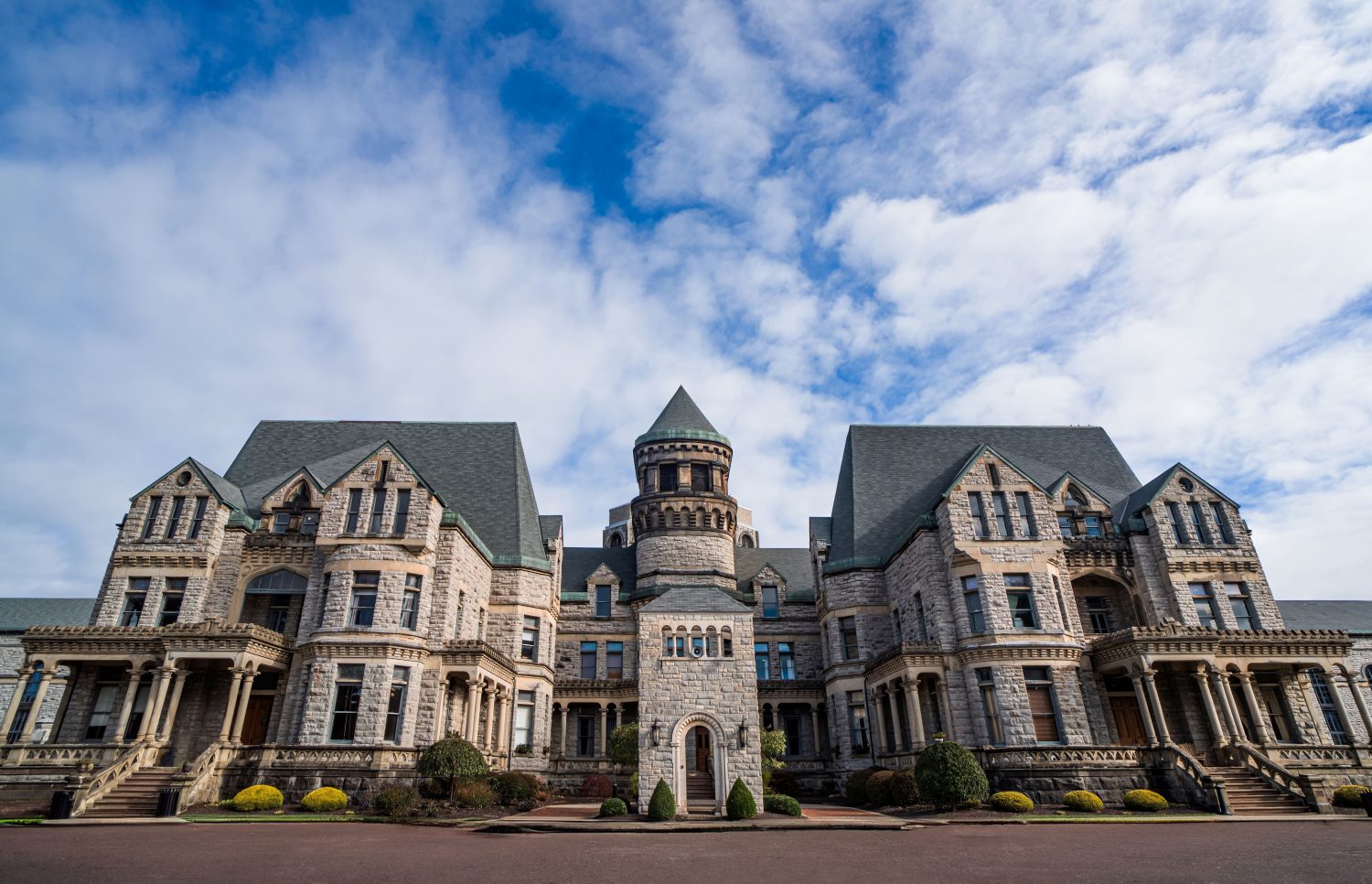 Historic stone prison building with central tower under clouds