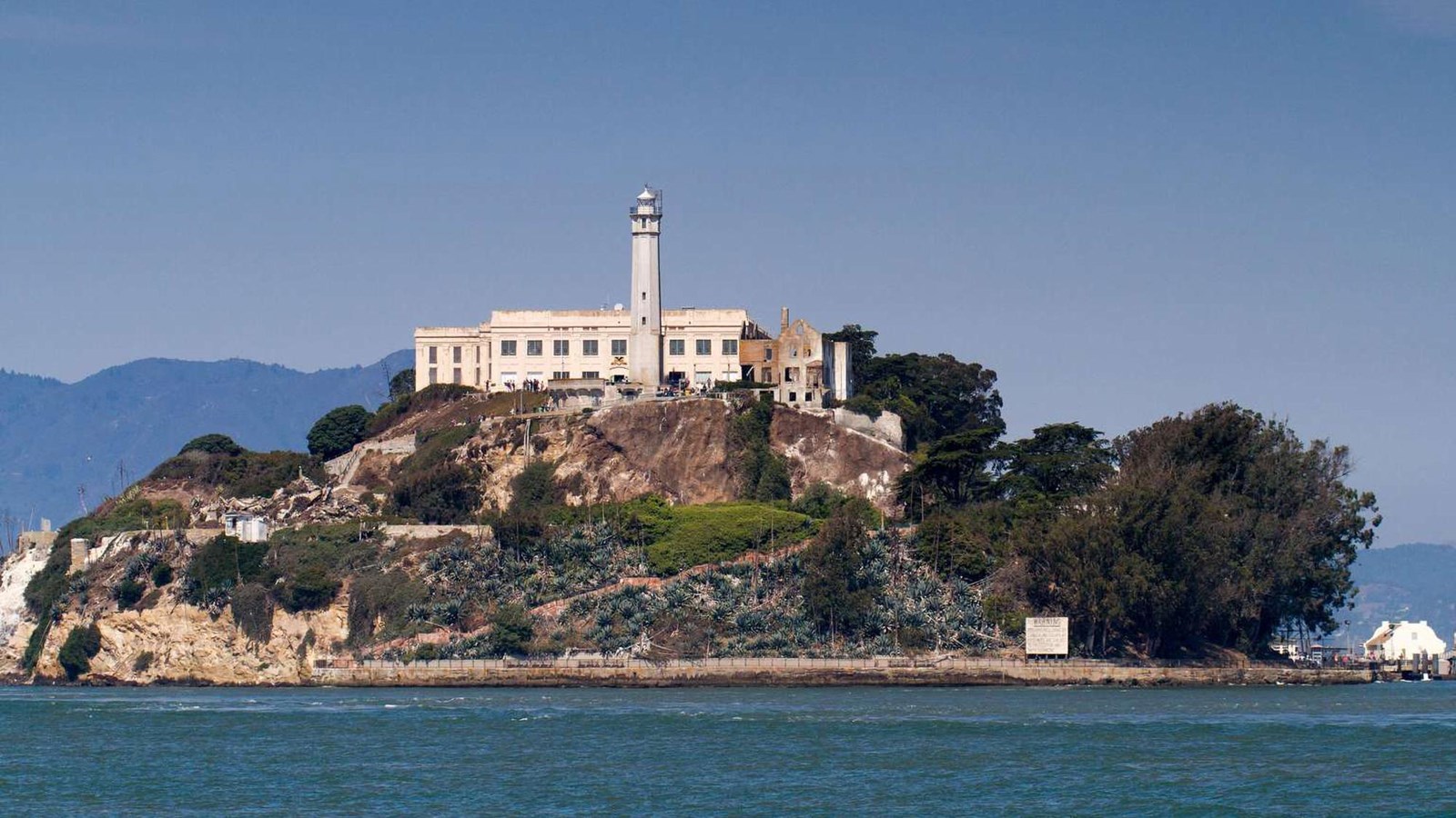Island prison complex with lighthouse above rocky shore